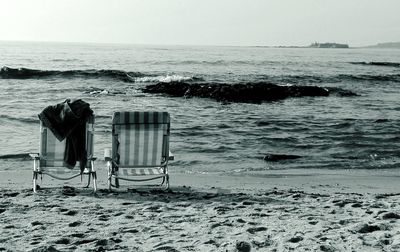 Chair on beach against sky