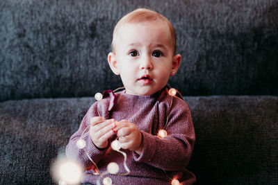 Portrait of cute baby boy sitting on sofa