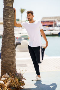 Full length of young man looking away while standing at harbor