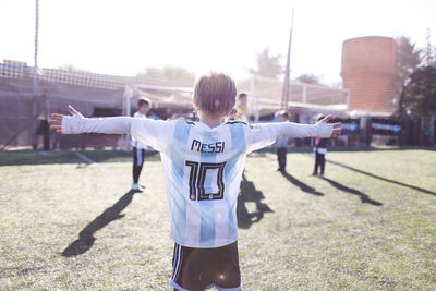 Rear view of person standing on field against sky