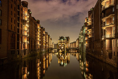 Panoramic view of canal amidst buildings in city at night