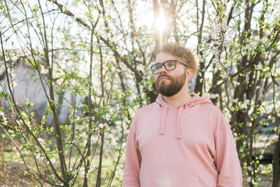 Portrait of young man wearing hat standing against trees