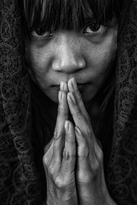 Close-up portrait of young woman with hands clasped