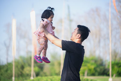 Father carrying daughter at park