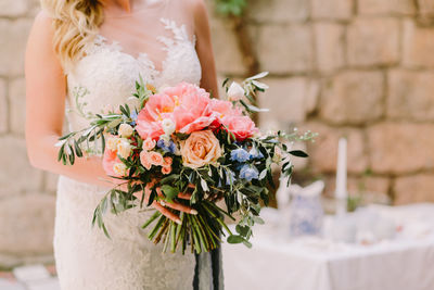 Midsection of bride holding flower bouquet