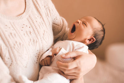 Young mother holding yawing baby on hands in room. good morning. motherhood.