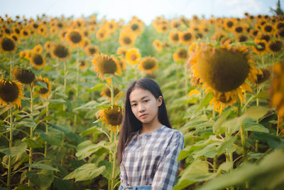 Portrait of young woman standing at sunflower farm
