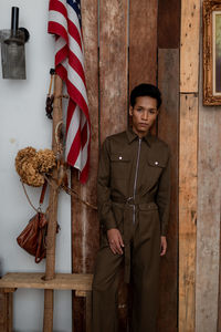 Portrait of young man wearing uniform standing by american flag