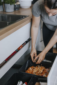 Woman putting rubbish into kitchen bin