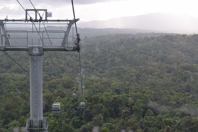 Overhead cable car in forest against sky