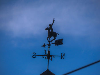 Low angle view of weather vane against sky