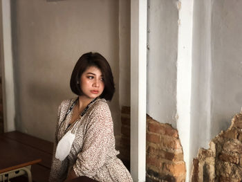 Portrait of woman standing against wall