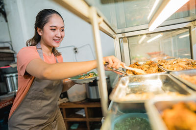 Portrait of smiling woman preparing food in kitchen