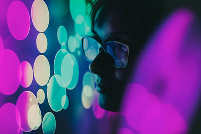 Close-up of woman in sunglasses by neon lights