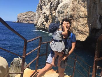 High angle view of mother carrying daughter on staircase against rock formation