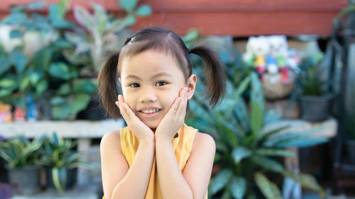 Positive charming 4 years old cute baby asian girl, little child with adorable pigtails hair smiling