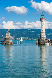 Lighthouse on building by sea against sky