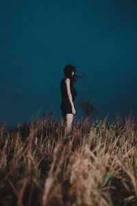 Side view of woman standing on field against sky