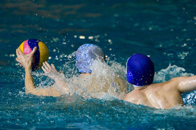 People playing with ball while swimming in pool