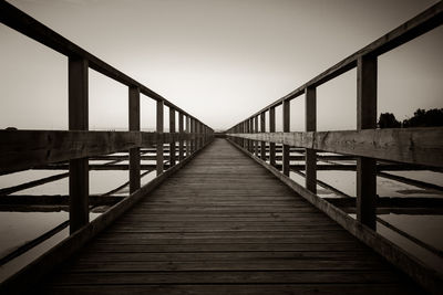 Footbridge in city against clear sky