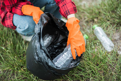 Midsection of woman collecting garbage in bag