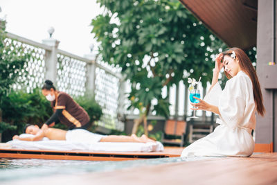 Young woman drinking glass while sitting outdoors