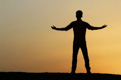 Silhouette man standing against orange sky