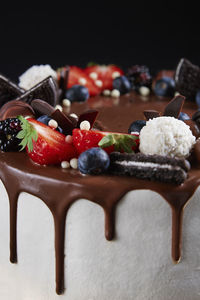 Cake decorated with strawberry and chocolate on dark background