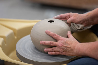 Close up of artist's hands shaping ceramic pottery on a potter's wheel