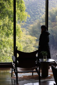 Silhouette of woman standing at the window with scenic bamboo forest in moganshan city.