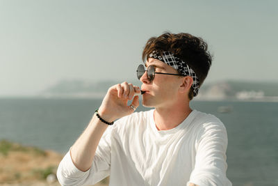 Young man looking away against sea