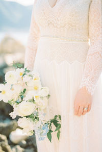 Midsection of bride holding bouquet