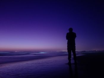 Silhouette man standing on beach against sky during sunset