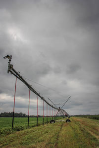 Crane on field against storm clouds