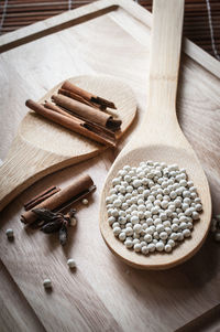 High angle view of white peppercorns with cinnamon and star anise on cutting board