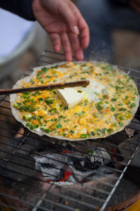 Cropped hand making pizza on barbecue