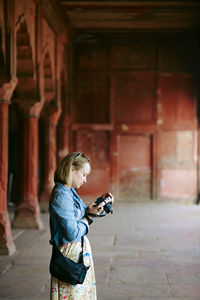 Side view of young woman standing against wall