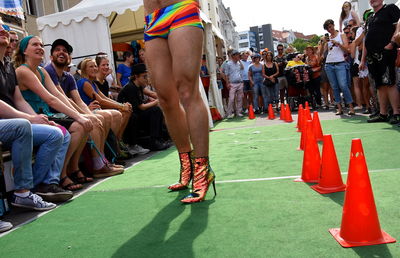 Low section of genderblend man wearing high heels standing in city