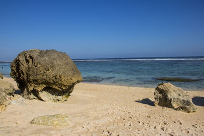 Rocks on beach against clear blue sky