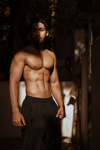 Portrait of shirtless young man standing outdoors