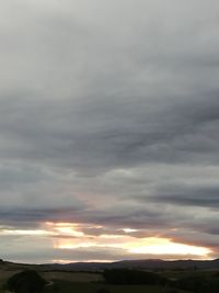 Storm clouds over landscape during sunset