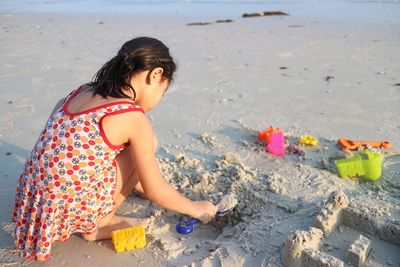 Rear view of girl making sandcastle at beach