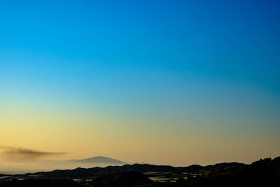 Scenic view of silhouette mountains against clear sky during sunset