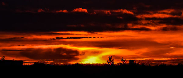 Silhouette built structure against dramatic sky during sunset