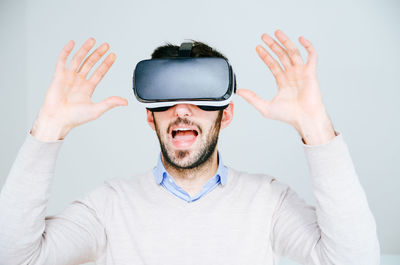 Portrait of man wearing virtual reality simulator against white background