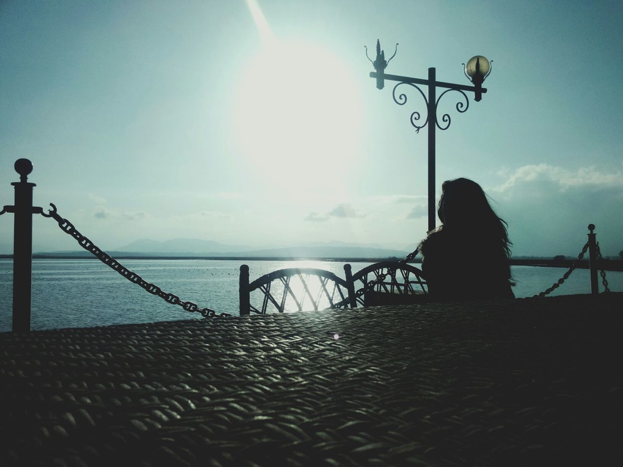 sea, water, silhouette, sky, tranquil scene, horizon over water, sun, tranquility, scenics, beauty in nature, sunlight, nature, pier, railing, idyllic, sunset, sunbeam, beach, street light, outdoors