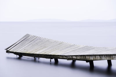 Wooden curved damaged jetty at the sea