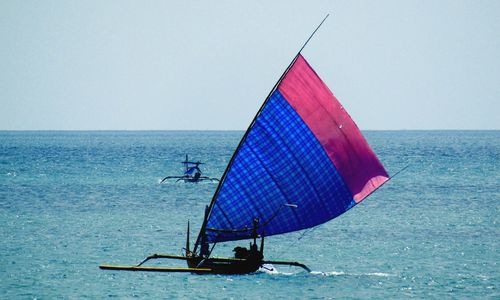 Sailboat in sea against clear sky