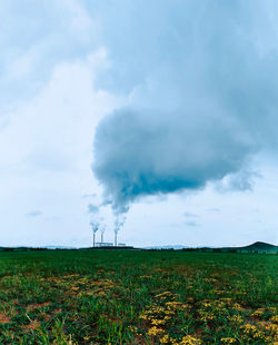 Smoke emitting from chimney on field against sky