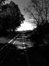 Empty road along silhouette trees